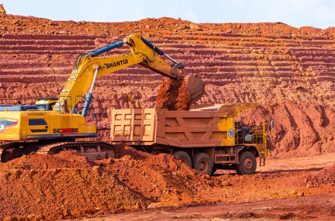 Excavator loading bauxite into a haul truck